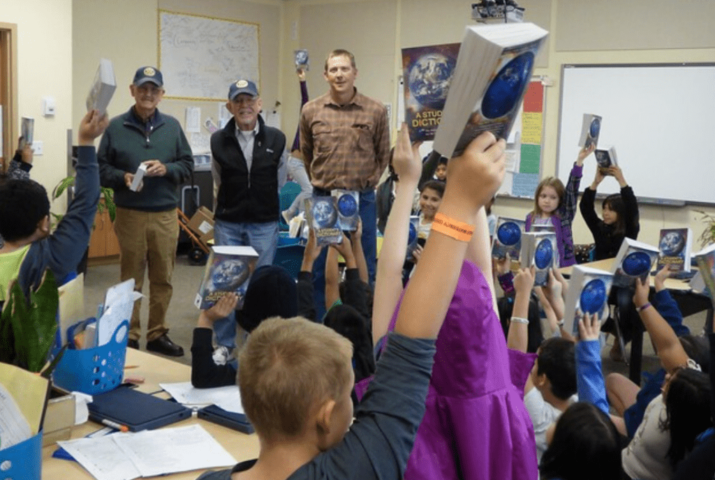 Rotary volunteers and students celebrating new dictionaries in a classroom